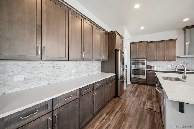 kitchen featuring backsplash, dark wood-style flooring, appliances with stainless steel finishes, a sink, and light countertops