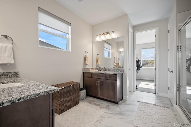 bathroom featuring a sink, a shower stall, marble finish floor, and two vanities