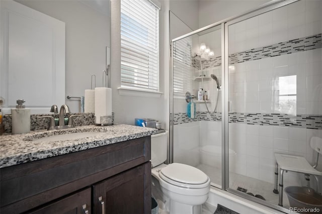 bathroom with toilet, a shower stall, and vanity