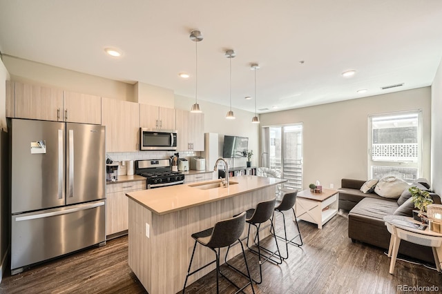 2374 S University Blvd Unit 204, Denver, CO 80210 - kitchen featuring appliances with stainless steel finishes, a sink, a kitchen bar, dark wood-style floors, and a center island with sink