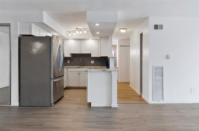 2 Adams St Unit 608, Denver, CO 80206 - kitchen featuring freestanding refrigerator, white cabinets, backsplash, light countertops, and light wood-style flooring