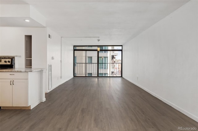 2 Adams St Unit 608, Denver, CO 80206 - unfurnished living room featuring a wall of windows, baseboards, and dark wood finished floors