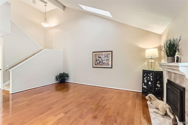 living room with a premium fireplace, vaulted ceiling with skylight, and hardwood / wood-style flooring