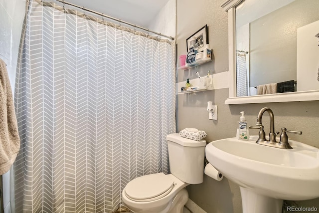 bathroom featuring sink, a shower with shower curtain, and toilet