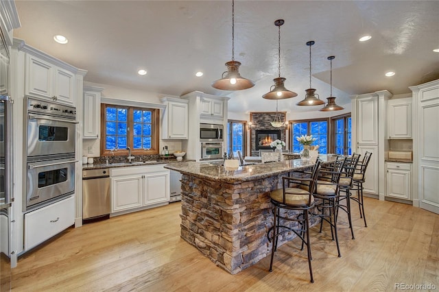 kitchen with sink, hanging light fixtures, stainless steel appliances, a center island, and white cabinets