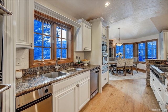 kitchen featuring appliances with stainless steel finishes, pendant lighting, white cabinetry, sink, and dark stone counters