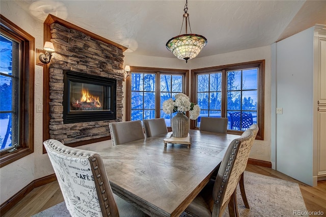 dining space featuring a textured ceiling, a fireplace, and light hardwood / wood-style flooring