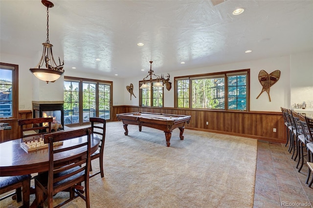 recreation room featuring a multi sided fireplace, pool table, a textured ceiling, and wood walls