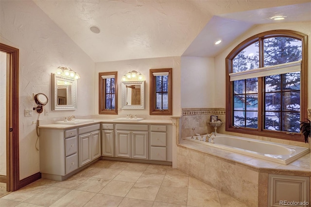 bathroom with lofted ceiling, vanity, a relaxing tiled tub, and tile patterned floors