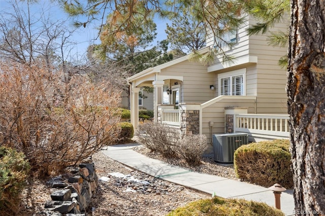 view of front facade featuring stone siding, central AC unit, and a porch