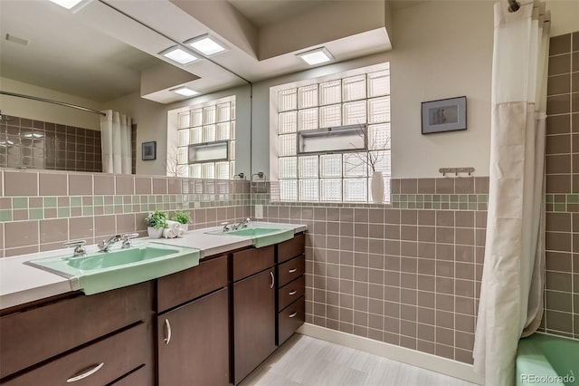 9650 W 35th Ave, Wheat Ridge, CO 80033 - bathroom featuring tile walls, double vanity, shower / bath combo, and a wainscoted wall