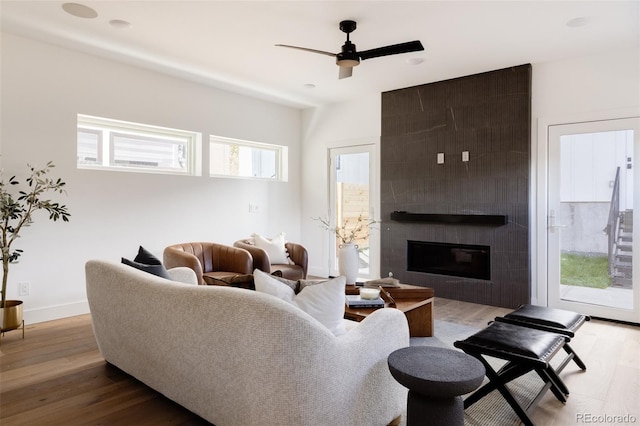 living room with hardwood / wood-style floors, a large fireplace, and ceiling fan