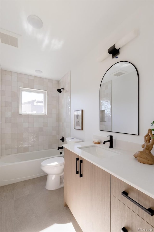 full bathroom featuring tiled shower / bath, tile patterned flooring, vanity, and toilet