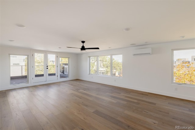 spare room with an AC wall unit, ceiling fan, hardwood / wood-style floors, and french doors