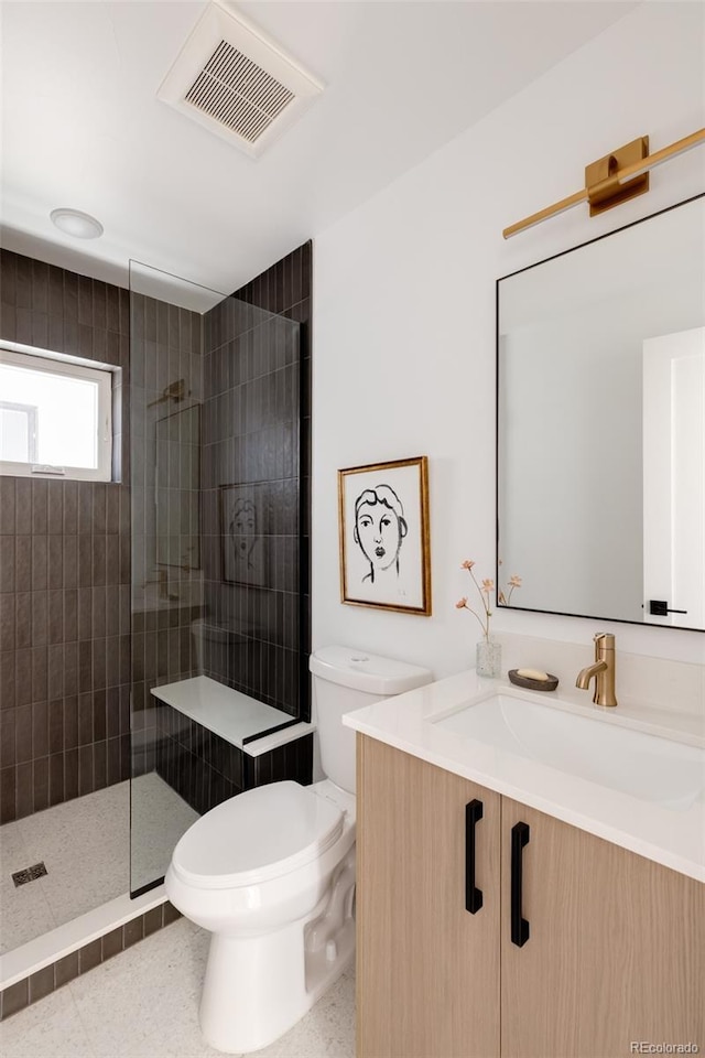 bathroom featuring vanity, toilet, and tiled shower