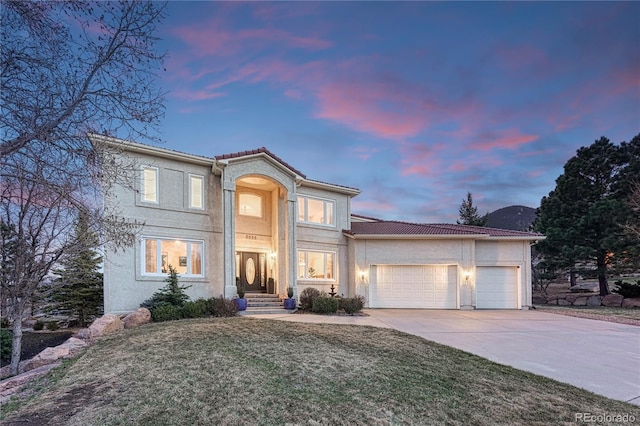3035 Blodgett Dr, Colorado Springs, CO 80919 - view of front of home with stucco siding, a front lawn, a tile roof, an attached garage, and concrete driveway