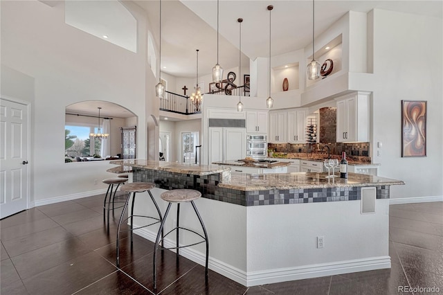 3035 Blodgett Dr, Colorado Springs, CO 80919 - kitchen with arched walkways, an inviting chandelier, a breakfast bar area, and a large island with sink