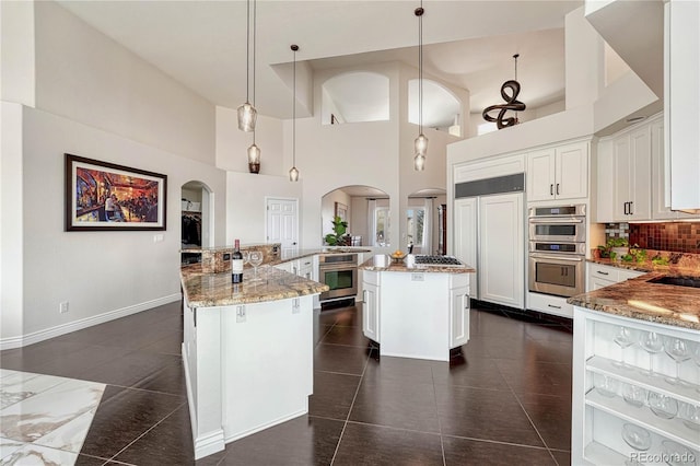 3035 Blodgett Dr, Colorado Springs, CO 80919 - kitchen with paneled refrigerator, double oven, arched walkways, a large island, and a high ceiling