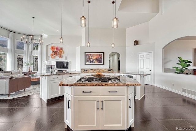 3035 Blodgett Dr, Colorado Springs, CO 80919 - kitchen with stainless steel gas cooktop, arched walkways, a high ceiling, and open floor plan