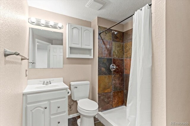 13244 Quivas St, Denver, CO 80234 - full bath with toilet, vanity, a tile shower, a textured wall, and a textured ceiling