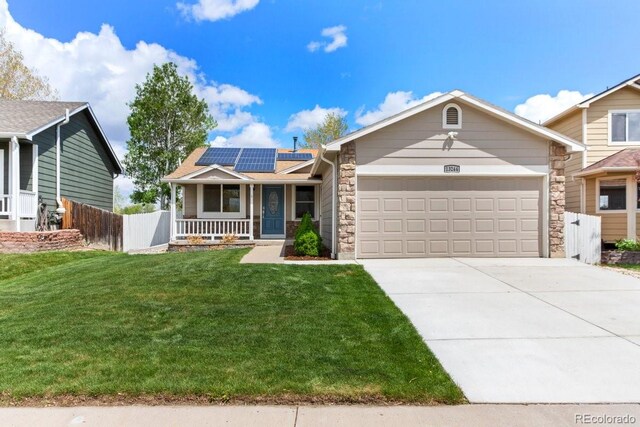 13244 Quivas St, Denver, CO 80234 - view of front of house featuring covered porch, an attached garage, stone siding, and roof mounted solar panels