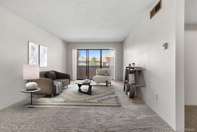 carpeted living room featuring visible vents, a textured wall, and a textured ceiling