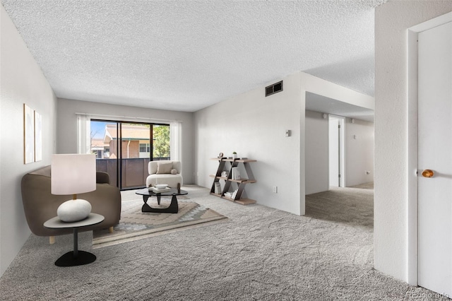 sitting room featuring a textured ceiling, carpet flooring, and visible vents