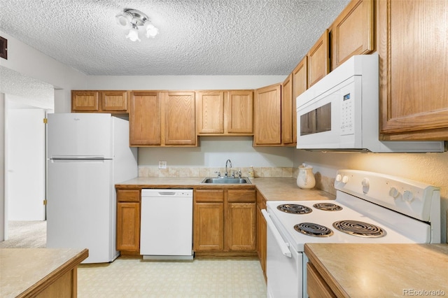 kitchen featuring white appliances, light countertops, a sink, and light floors