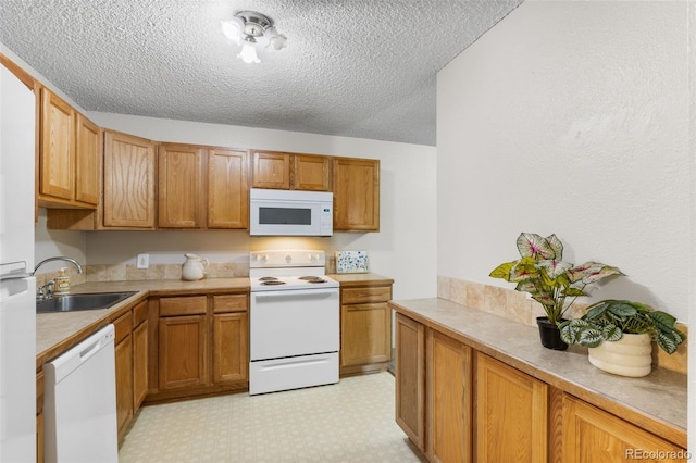 kitchen with brown cabinets, white appliances, light countertops, and a sink