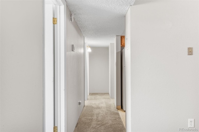 hall with light carpet and a textured ceiling