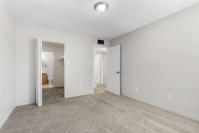 unfurnished bedroom with a textured ceiling, carpet floors, and visible vents