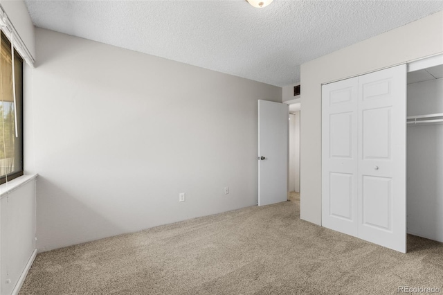 unfurnished bedroom with carpet, a closet, visible vents, and a textured ceiling