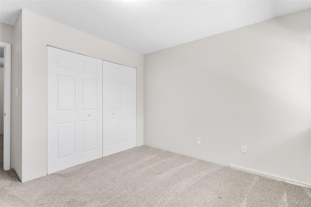 unfurnished bedroom with carpet floors, a closet, and a textured ceiling