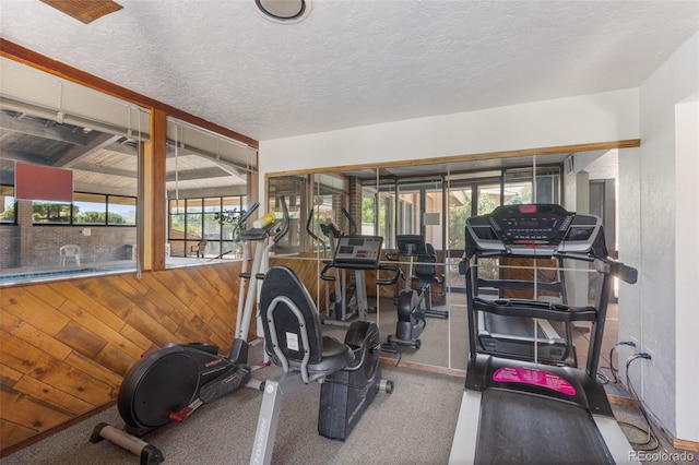 gym with wood walls and a textured ceiling