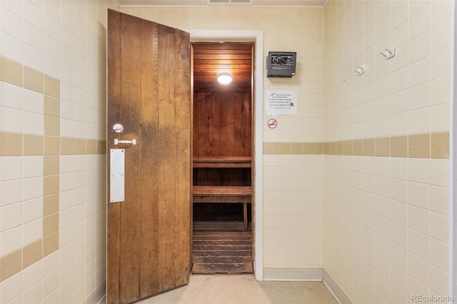 corridor featuring a sauna, tile walls, and light colored carpet