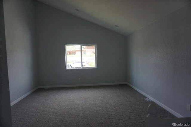 carpeted empty room featuring vaulted ceiling and baseboards