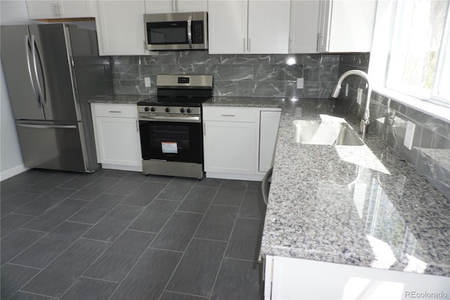 kitchen featuring stainless steel appliances, a sink, white cabinetry, and tasteful backsplash