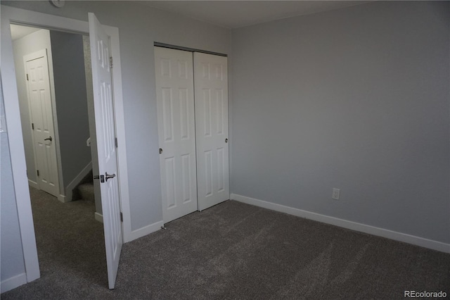 unfurnished bedroom featuring dark colored carpet, baseboards, and a closet