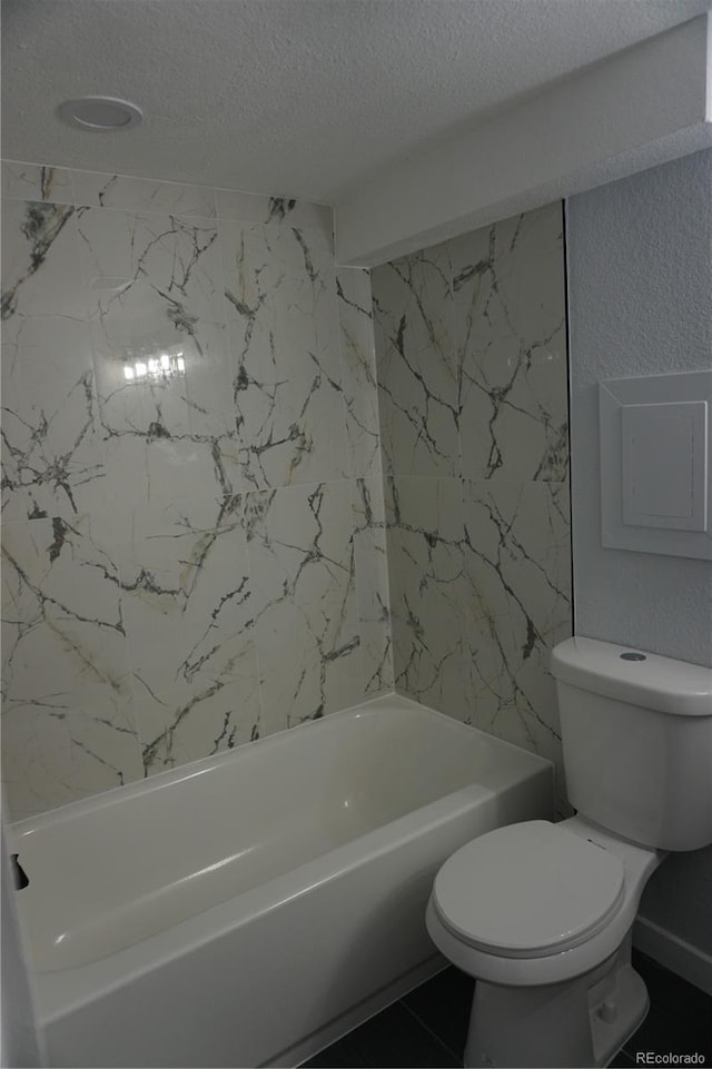 bathroom featuring a textured ceiling, toilet, a bath, and a textured wall