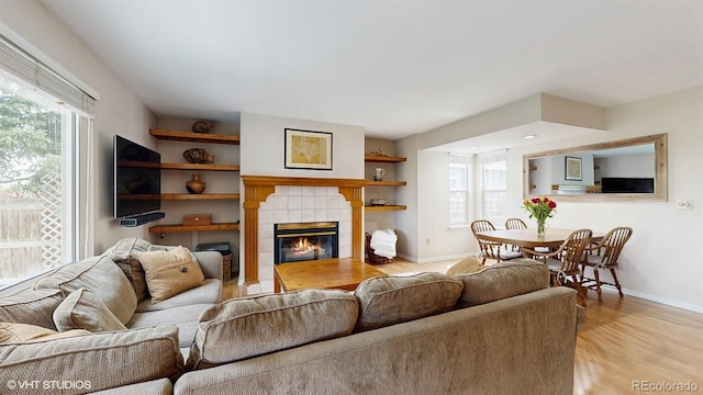 living area featuring baseboards, a fireplace, and light wood-type flooring