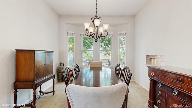 dining room featuring a chandelier, light carpet, and baseboards