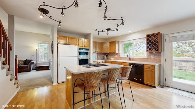 kitchen with black appliances, light wood-style floors, light countertops, and a center island