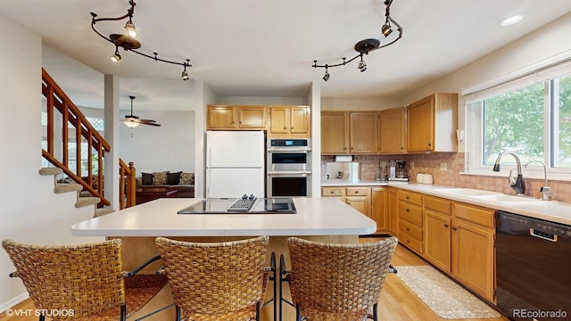 kitchen featuring black appliances, a sink, rail lighting, and light wood-style floors