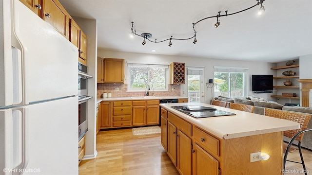 kitchen with freestanding refrigerator, black electric stovetop, a center island, and light countertops