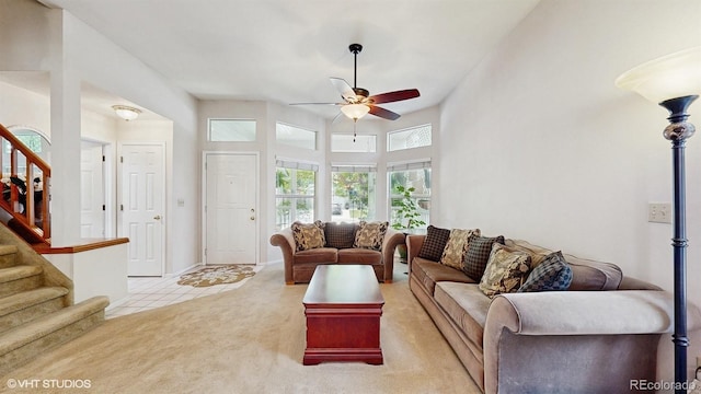 carpeted living area featuring ceiling fan and stairway