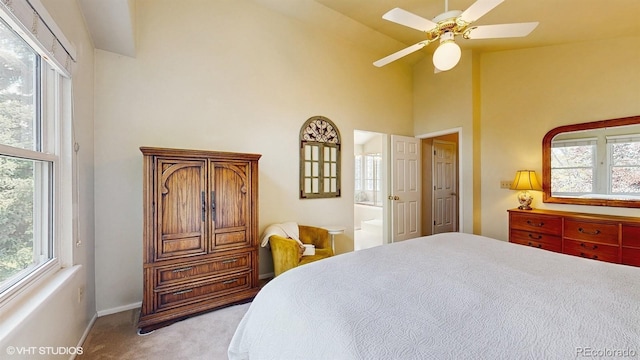 carpeted bedroom with high vaulted ceiling, baseboards, ensuite bathroom, and a ceiling fan