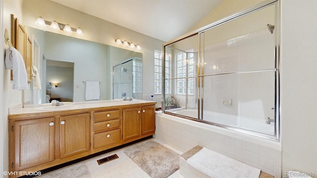 full bathroom featuring ensuite bathroom, vaulted ceiling, double vanity, and tiled shower / bath combo