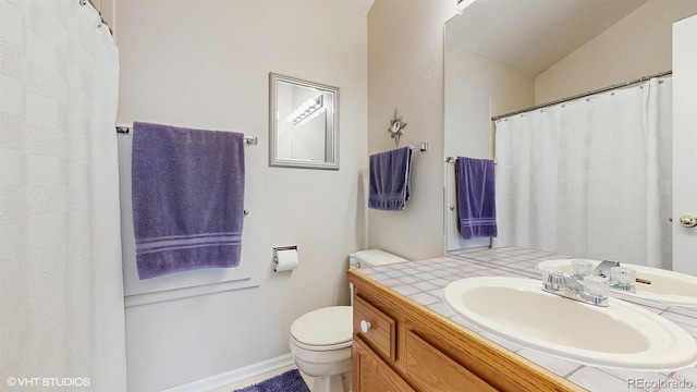 full bathroom with toilet, vanity, and baseboards