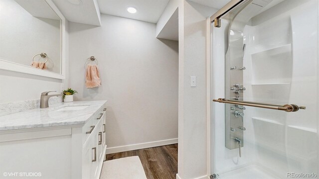 full bath featuring a stall shower, wood finished floors, vanity, and baseboards