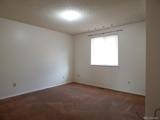 carpeted empty room with a textured ceiling